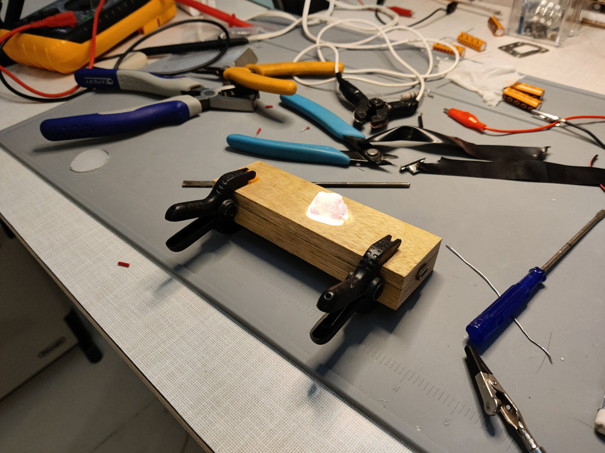 Wooden block with clamps on a workbench with tools and wires in the background