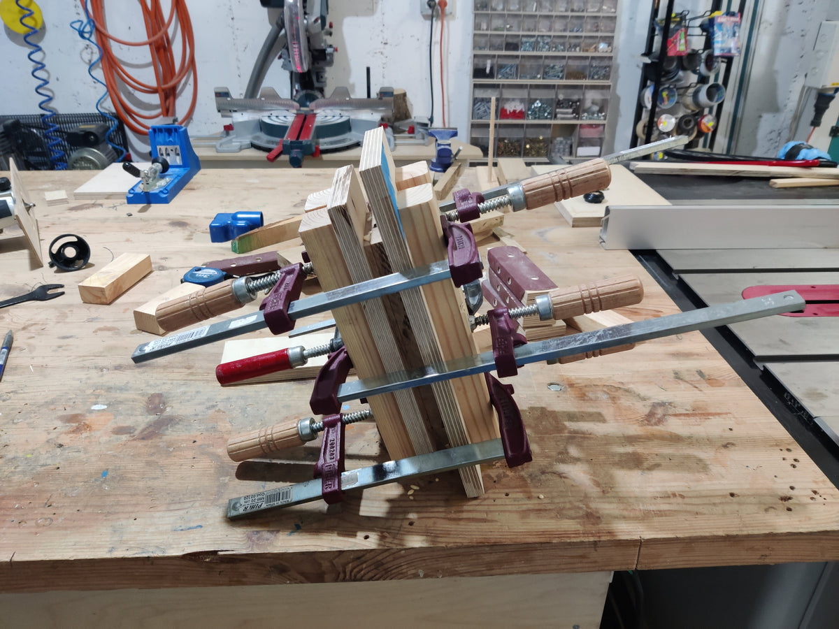 Wooden frame held together with clamps on a workshop table